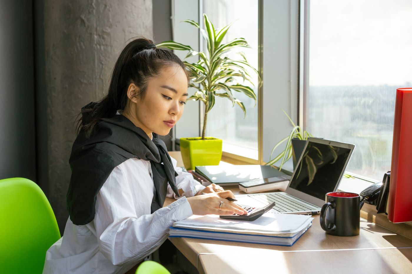 A finance officer working with a calculator and a laptop