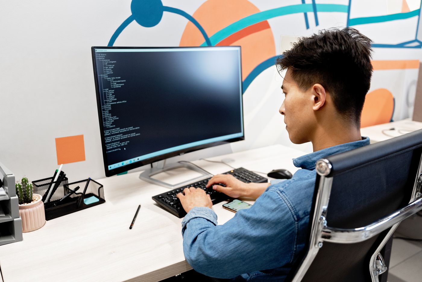 An engineer at work at a desk with a large monitor