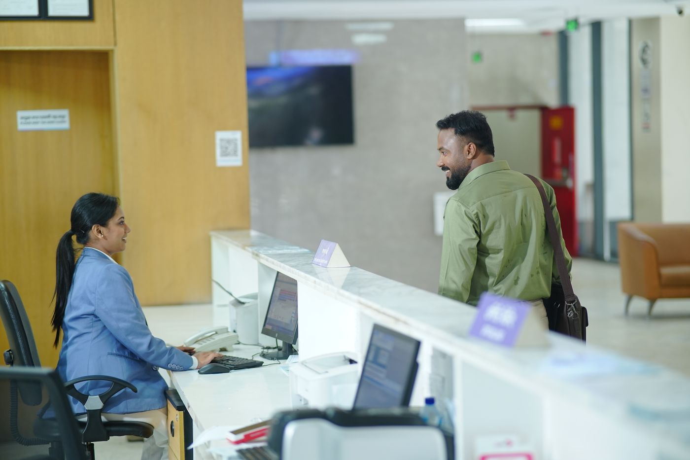 A receptionist at a front desk computer as a guest arrives